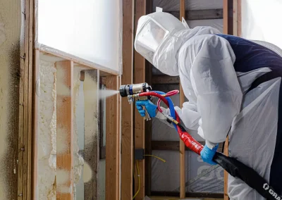 technician-wearing-protective-gear-spraying-polyurethane-insulation-into-open-wall-studs