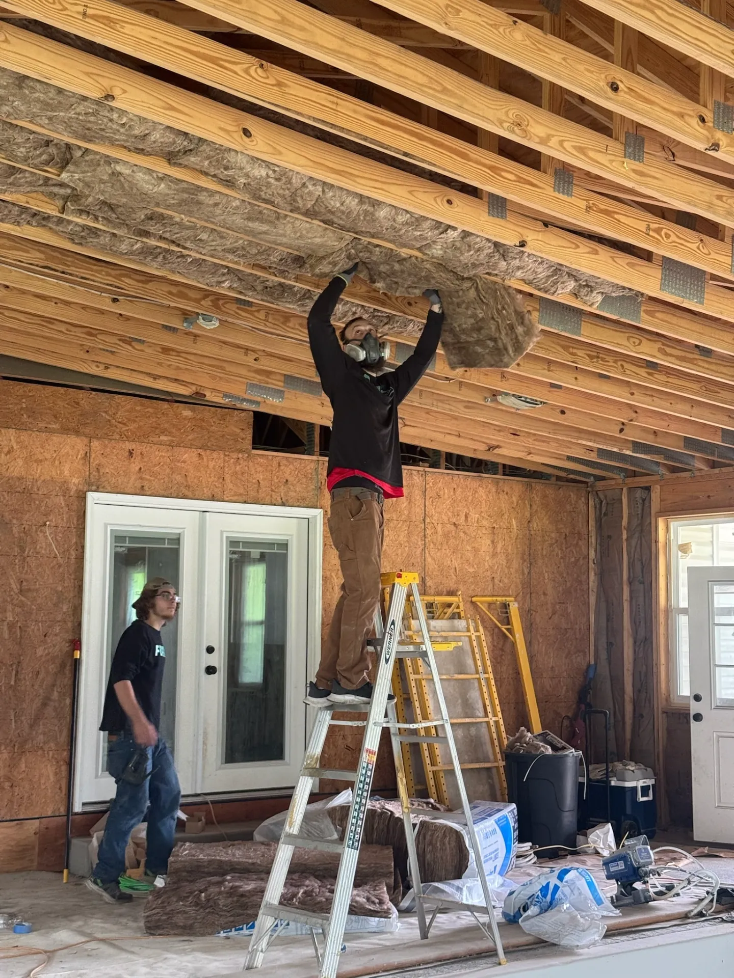 technicians-installing-fiberglass-insulation-batts-between-exposed-ceiling-joists